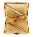 Cigarette case open to show gold interior, springs used to hold cigarettes affixed diagonally o…