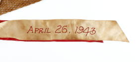 White ribbon with "April 26, 1943" red embroidered text