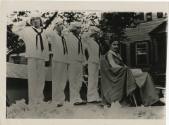 Black and white photograph of four boys in sailor uniforms standing behind a seated woman