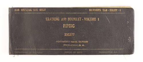 Printed manual with black cover and gold lettering that reads "Training Aid Booklet - Volume 1 …