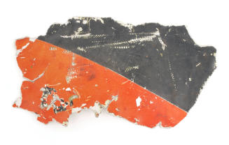 Metal shrapnel from a Regulus I missile, orange and black paint divided diagonally, jagged edge…