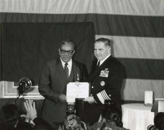 Black and white photograph of Alonzo Swann, a Black man, receiving a Navy Cross certificate fro…