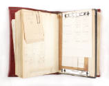 Interior of red leather bound logbook with notes paperclipped to pages