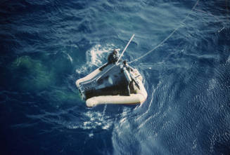 Color image of Gemini 3 capsule in the water with yellow flotation device surrounding it