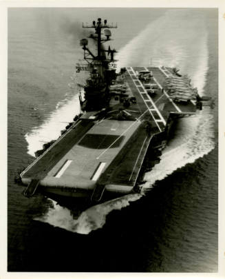 Black and White photograph of aircraft carrier USS Intrepid at sea with aircraft parked on the …