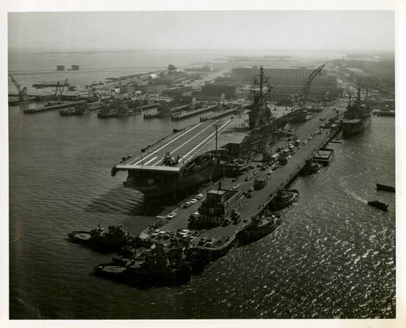 Black and white photograph of USS Intrepid docked in Norfolk, Virginia