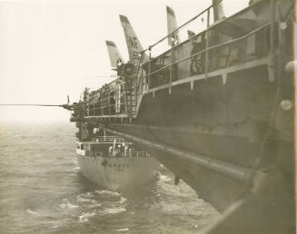 Black and white photograph of a tanker directly behind USS Intrepid at sea