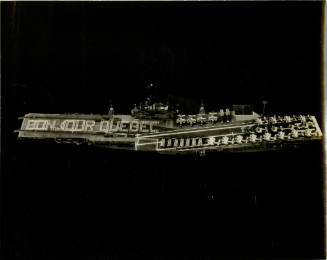 Black and white aerial photograph of USS Intrepid at sea with sailors lined up to spell "Bonjou…