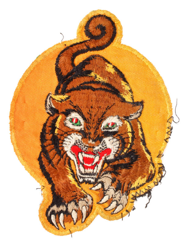 Embroidered circular yellow patch depicting a tiger advancing forward with teeth bared and claw…