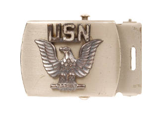 Silver belt buckle with raised imagery of eagle with spread wings below raised text that reads …