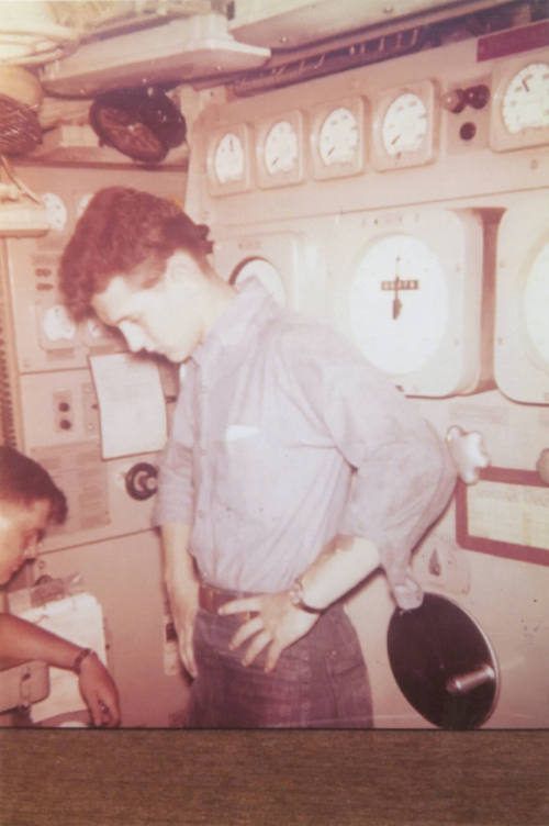 Printed color photograph of two sailors in the maneuvering room on the submarine USS Growler