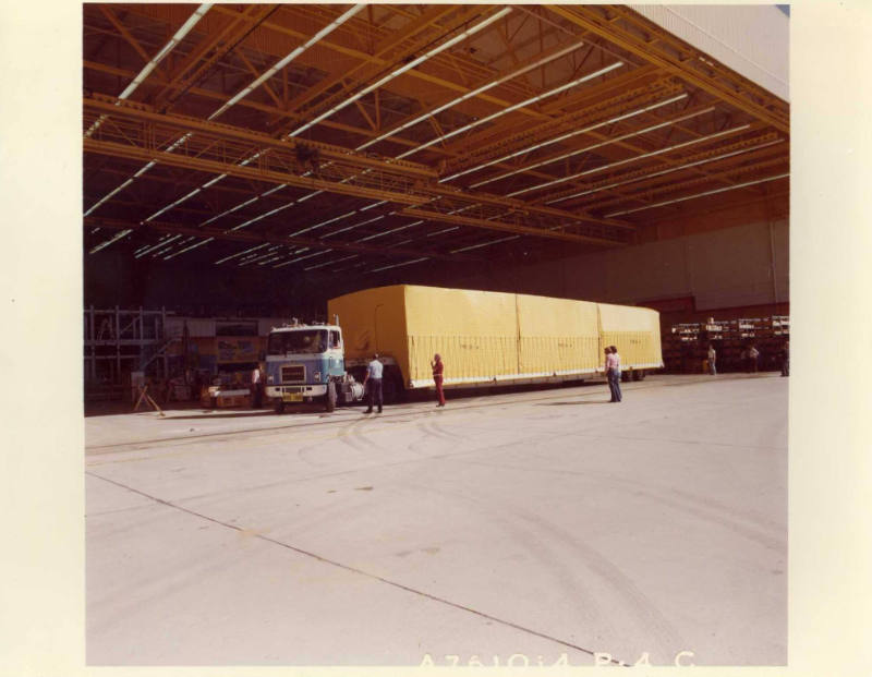 Color photograph of the Enterprise Mid-body arriving at Palmdale Assembly Facility on a truck