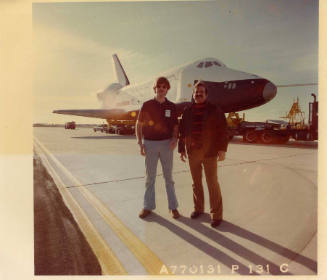Color photograph of two men standing in front of Enterprise