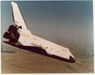 Color photograph of Enterprise in a nose dive over the desert