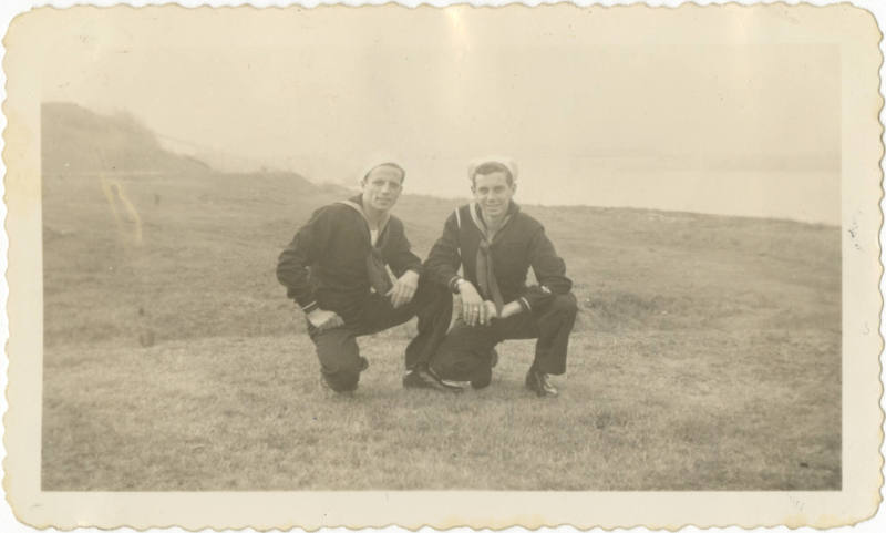 Black and white photograph of two sailors in dress blue uniforms posing in a field