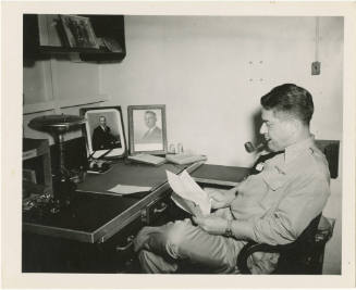 Black and white photograph of Captain Joseph F. Bolger seated at his desk on board USS Intrepid