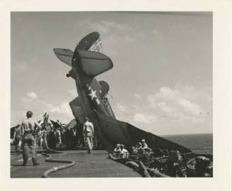 Black and white photograph of an airplane that taxied over the edge of the flight deck with its…