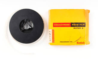 Image of black Super 8 film reel and yellow cardboard Kodak box