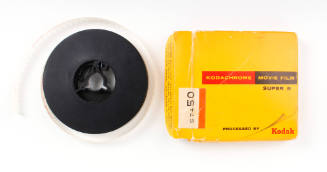 Image of black Super 8 film reel and yellow cardboard Kodak box