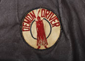 Detail of circular white "Demon Driver" patch with image of red cloaked figure