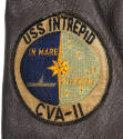 Detail of circular USS Intrepid seal patch, showing aircraft carrier at sea bisected with sky a…