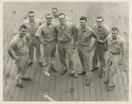 Printed black and white photograph of eight USS Intrepid officers standing on the flight deck a…