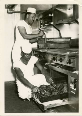 Black and white photograph of two Black cooks in a ship's galley
