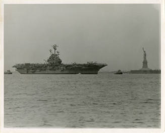 Black and white photograph of USS Intrepid passing the Statue of Liberty