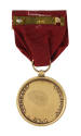 Back of Navy Good Conduct Medal with red ribbon and raised text that reads “Fidelity – Zeal – O…