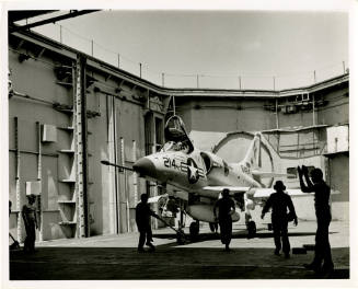 Black and white photograph of a Douglas A-4 Skyhawk on the forward aircraft elevator at the han…