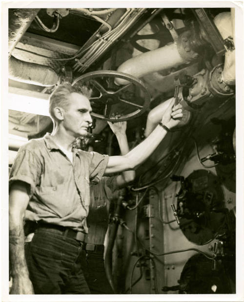 Black and white photograph of a crewmember working in a fire room