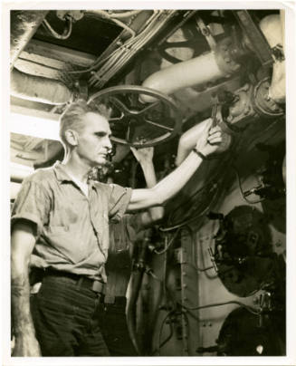 Black and white photograph of a crewmember working in a fire room