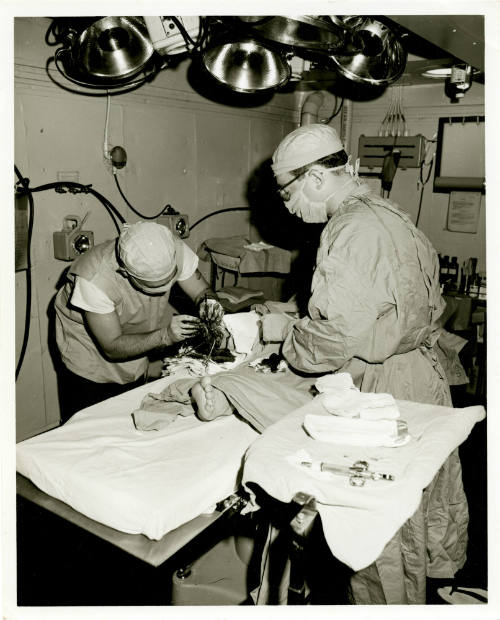Black and white photograph of two men in scrubs during a training surgery in sick bay