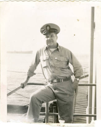 Chief Petty Officer Charles O'Day leaning on a railing onboard a naval vessel