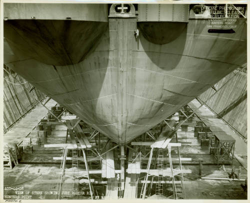 Black and white photograph of USS Intrepid in dry dock, view from the stern