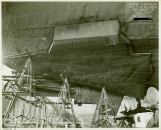 Black and white photograph of a large shell patch on the hull of USS Intrepid after torpedo att…