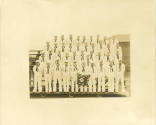 Black and white group photograph of gunner's mate school sailors standing on bleachers in four …