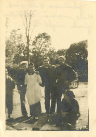 Printed black and white photograph of three sailors with two women and a man in a park in Japan
