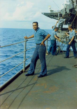 Color photograph of Agustin Ramos standing on a sponson with the ocean in the background