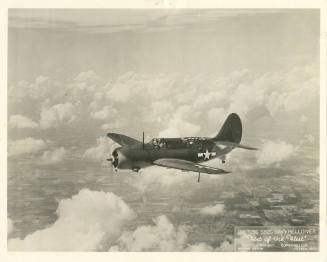Printed black and white photograph of a Curtiss SB2C Helldiver in flight