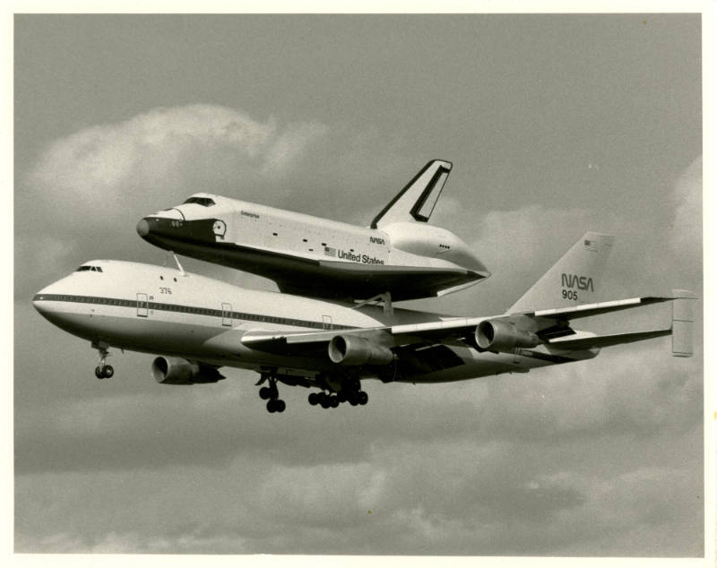 Printed black and white photograph of Enterprise on the back of a Boeing 747 mid flight