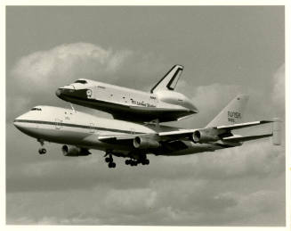 Printed black and white photograph of Enterprise on the back of a Boeing 747 mid flight