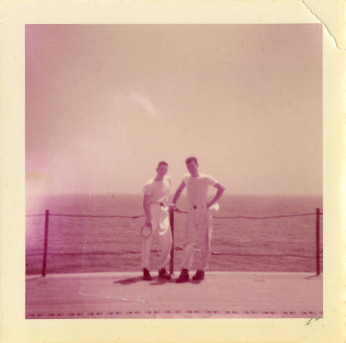 Printed color image of two sailors standing on USS Intrepid's flight deck