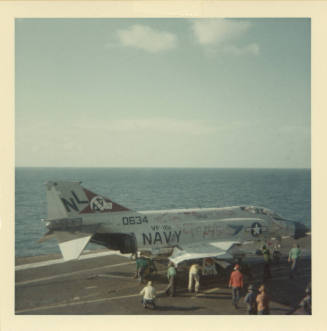 Color photograph of a F-4 Phantom with graffiti on Intrepid's flight deck