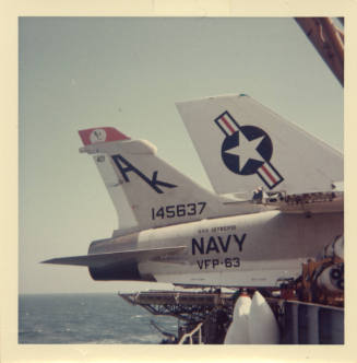 Color photograph of the tail of a Vought RF-8G Photo Crusader on Intrepid's flight deck