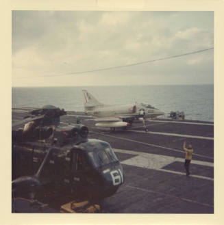 Color photograph of an a-4 Skyhawk and a Sea King on Intrepid's flight deck