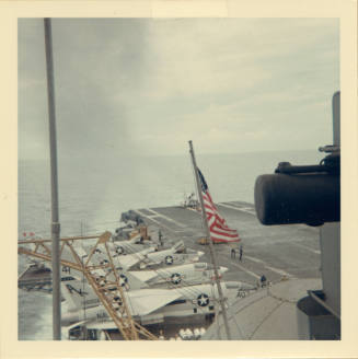 Color photograph of an aircraft landing on Intrepid's flight deck with other aircraft parked on…