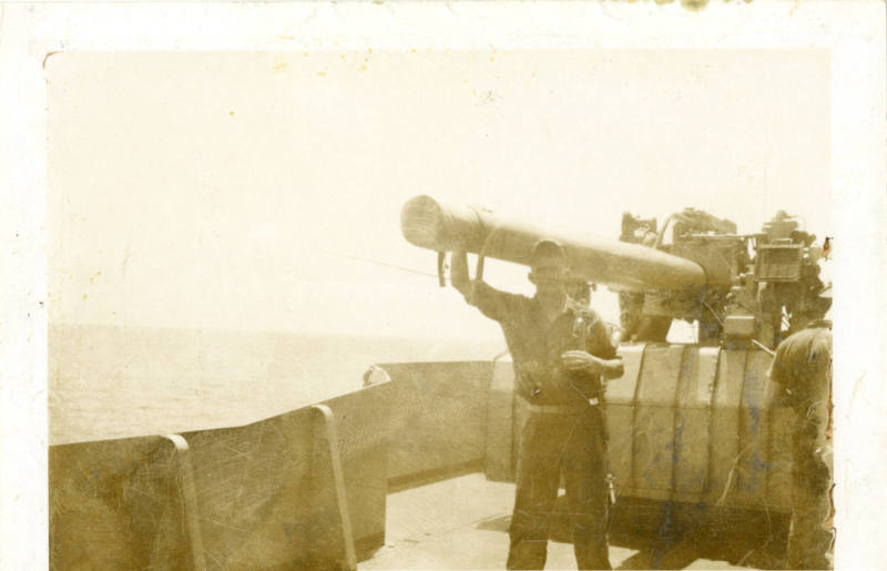 Black and white photograph of a Marine posing with a ship's anti-aircraft gun