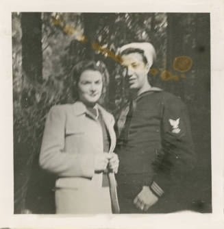 Printed black and white photograph of sailor Gilbert J. Farmer and a woman standing in front of…