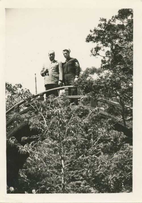 Printed black and white photograph of sailor Gilbert J. Farmer and a man in a suit standing on …